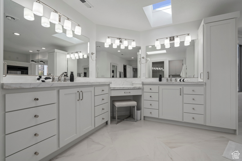Bathroom featuring dual bowl vanity, a skylight, and tile flooring