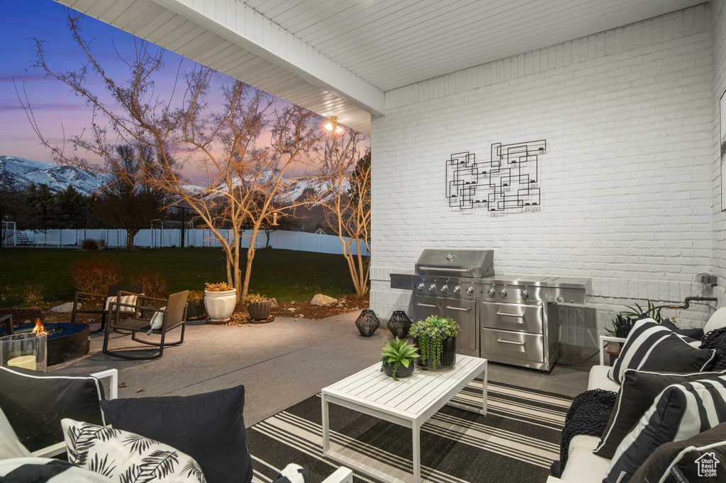 Patio terrace at dusk with an outdoor fire pit and a yard