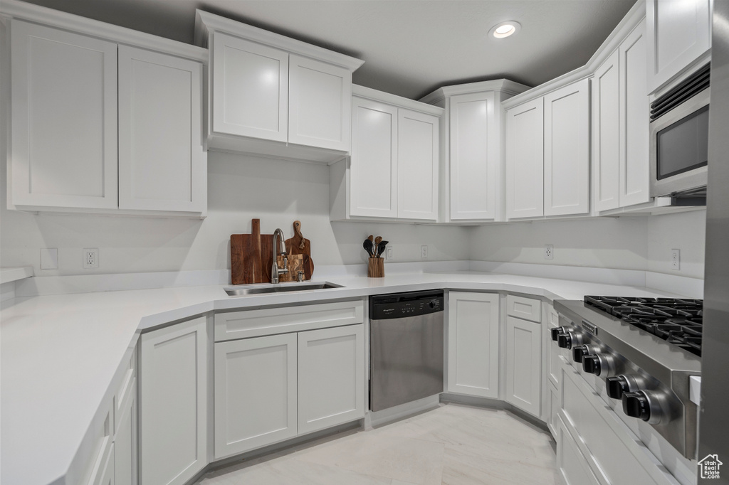 Kitchen featuring stainless steel appliances, white cabinets, sink, and light tile floors