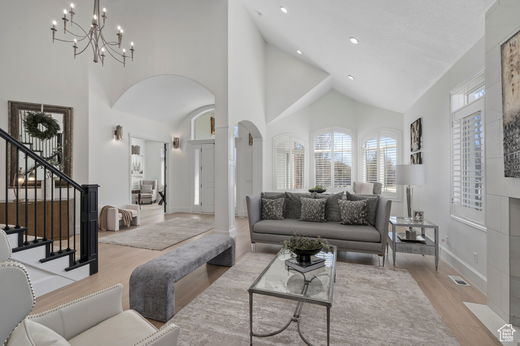 Living room featuring light hardwood / wood-style floors, high vaulted ceiling, and an inviting chandelier