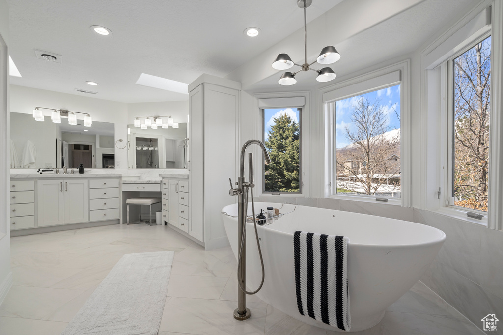 Bathroom featuring a notable chandelier, vanity, a bathtub, and tile floors