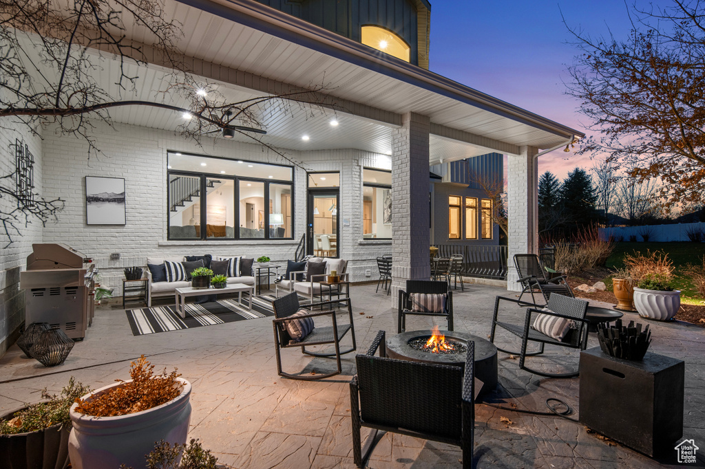 Patio terrace at dusk with a grill, exterior kitchen, and an outdoor living space with a fire pit
