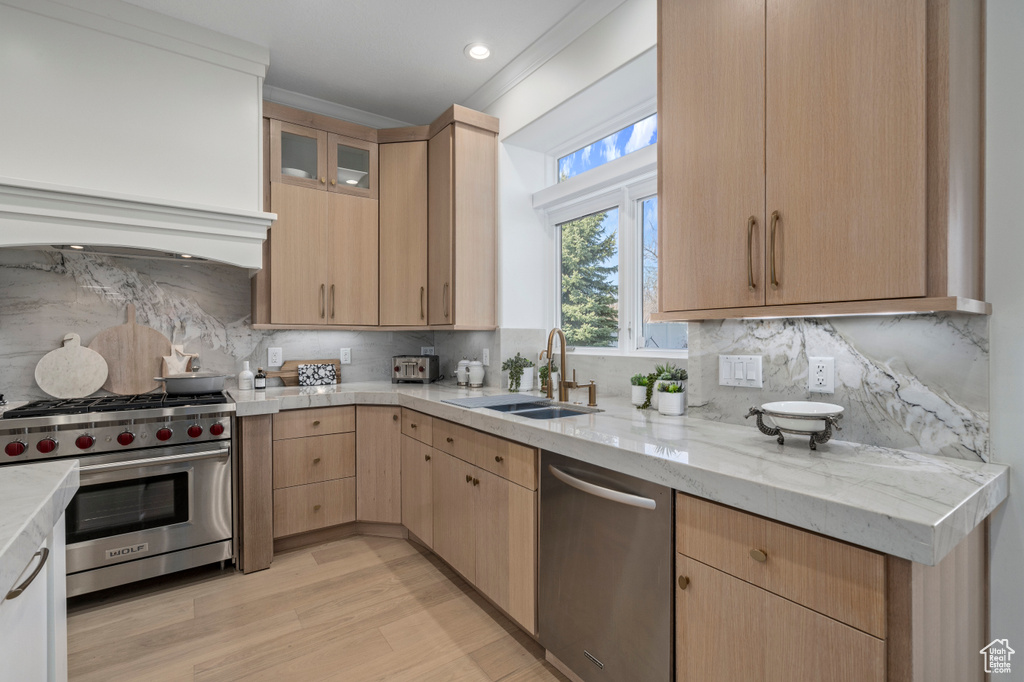 Kitchen featuring light stone counters, stainless steel appliances, backsplash, light brown cabinets, and sink