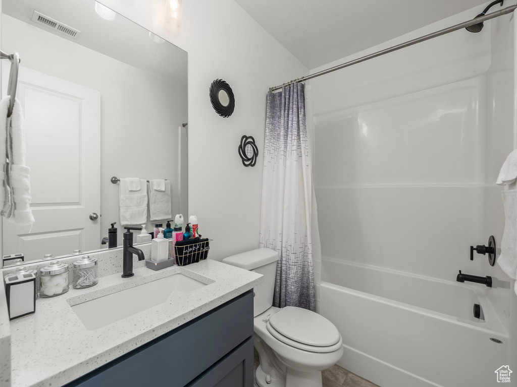 Full bathroom with shower / bath combo, tile floors, large vanity, and toilet