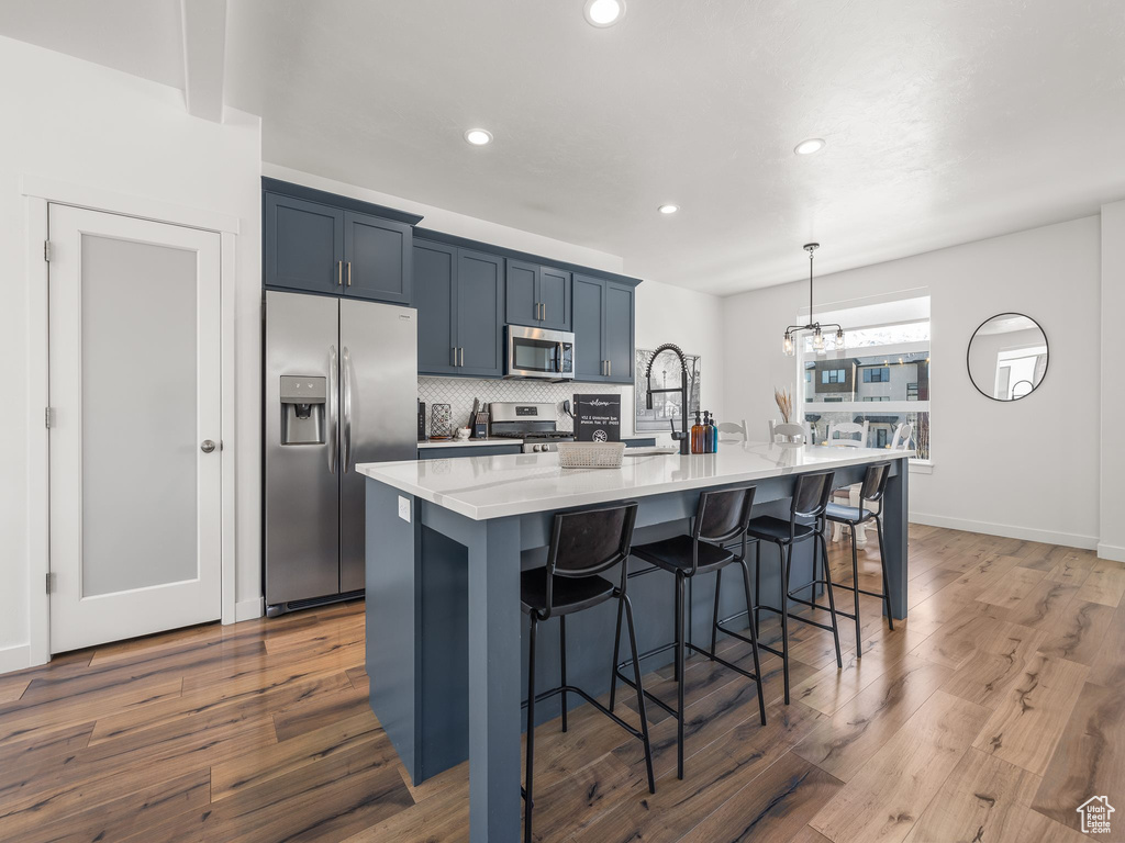 Kitchen with stainless steel appliances, a notable chandelier, dark wood-type flooring, and a breakfast bar