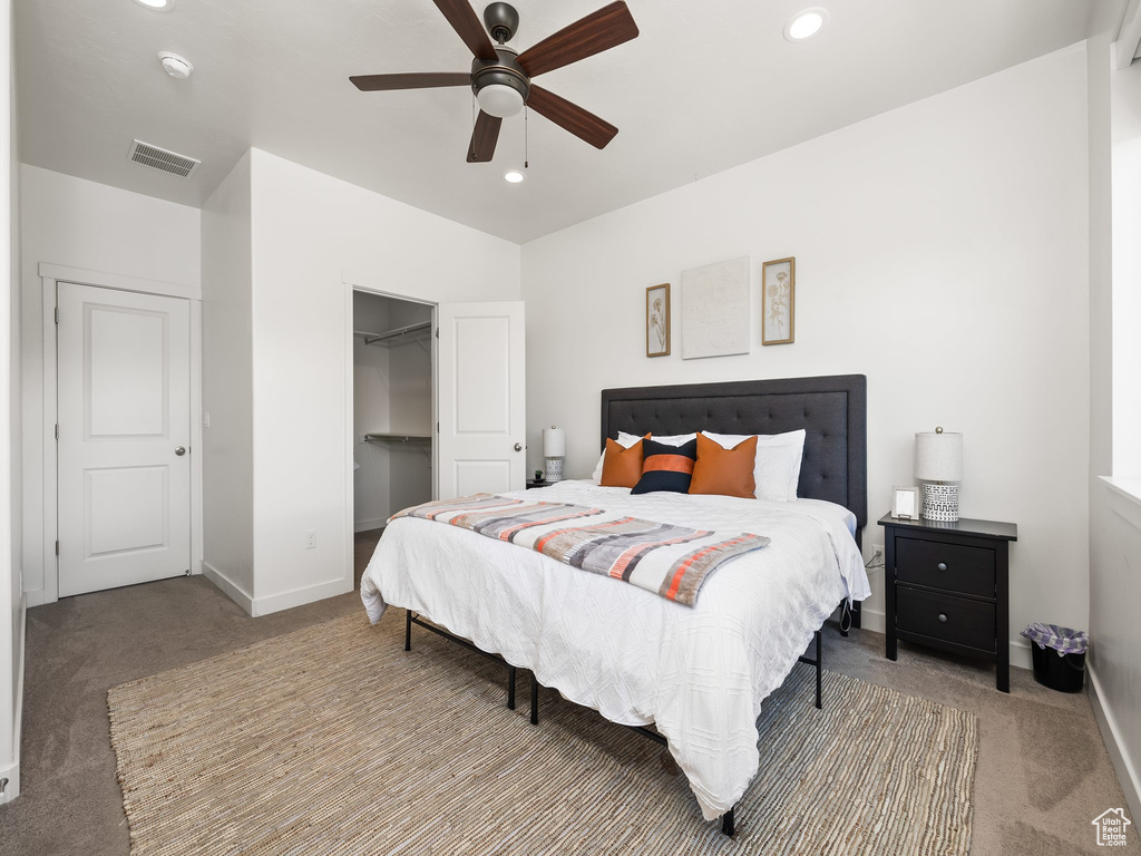 Carpeted bedroom with ceiling fan, a closet, and a spacious closet