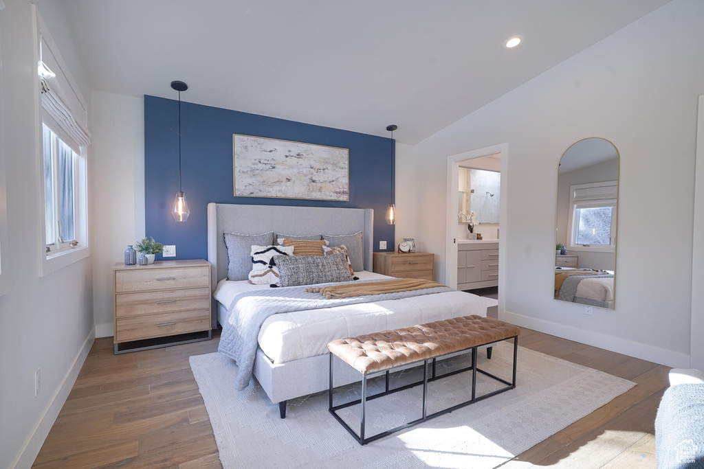 Bedroom with connected bathroom, vaulted ceiling, and hardwood / wood-style flooring