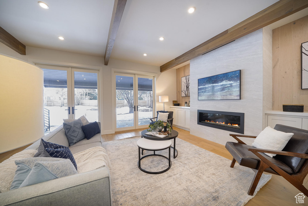 Living room featuring beamed ceiling, light hardwood / wood-style flooring, and a large fireplace