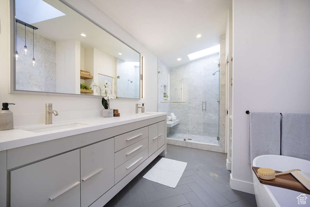 Bathroom featuring a skylight, double sink vanity, independent shower and bath, and tile flooring