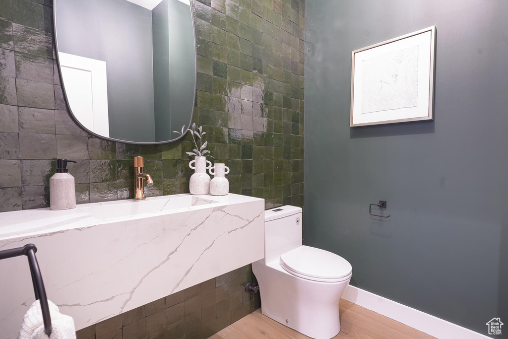Bathroom featuring tile walls, wood-type flooring, toilet, and vanity