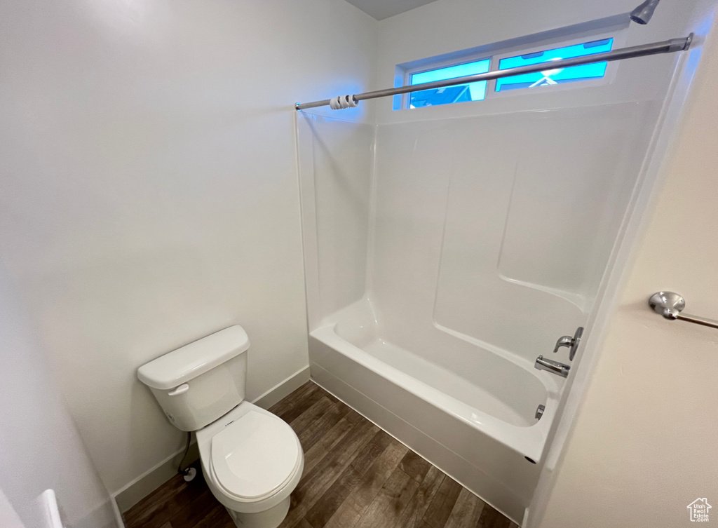 Bathroom featuring toilet, washtub / shower combination, and hardwood / wood-style flooring