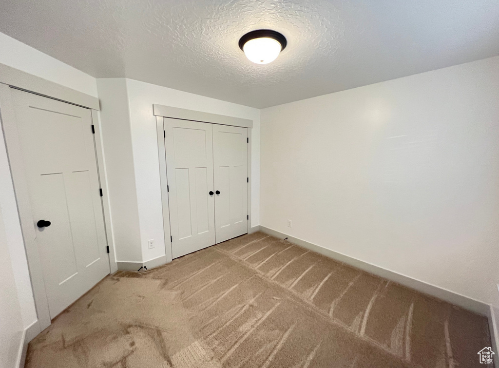 Unfurnished bedroom featuring light carpet and a textured ceiling