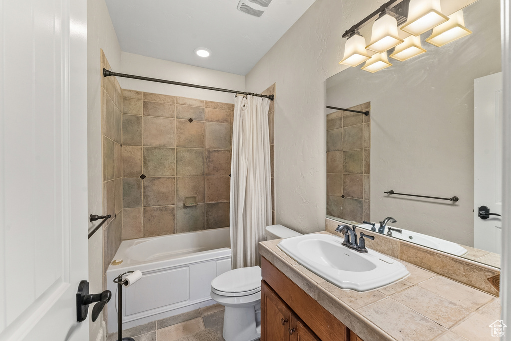 Full bathroom with tile flooring, toilet, oversized vanity, and shower / tub combo