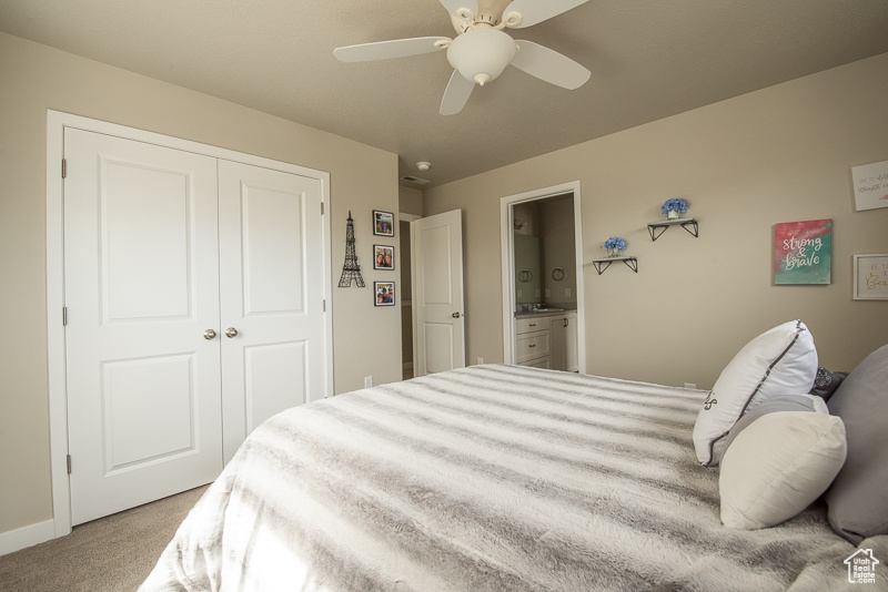 Carpeted bedroom with a closet, connected bathroom, and ceiling fan