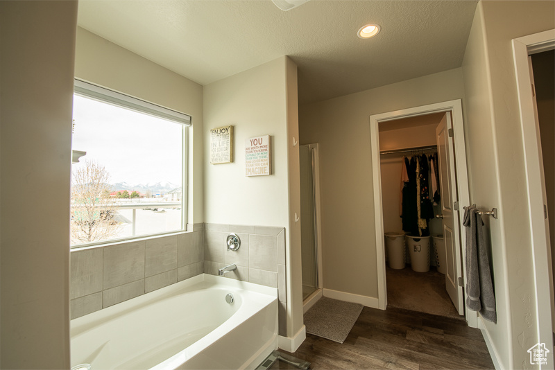 Bathroom with a textured ceiling, plus walk in shower, and hardwood / wood-style floors