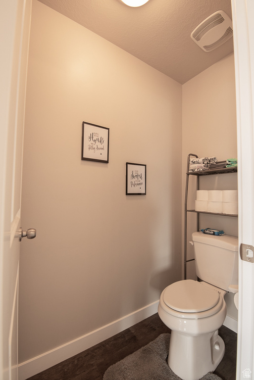 Bathroom featuring a textured ceiling, wood-type flooring, and toilet