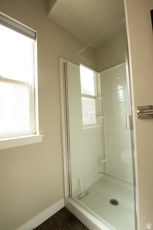 Bathroom featuring toilet, a healthy amount of sunlight, a shower with shower door, and hardwood / wood-style flooring