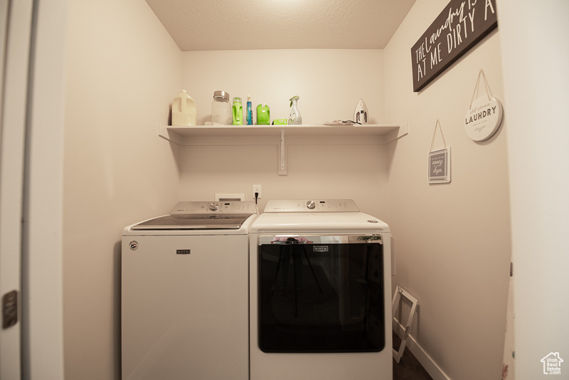 Laundry area with washing machine and dryer, a textured ceiling, and hookup for a washing machine