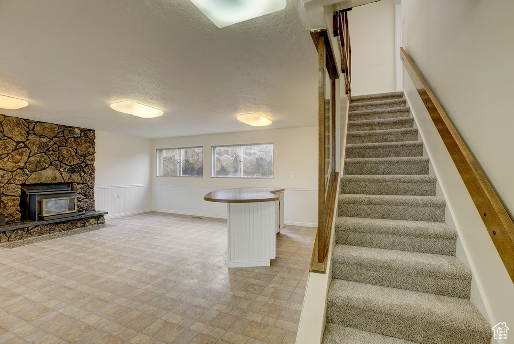 Staircase with light tile flooring, a textured ceiling, and a fireplace