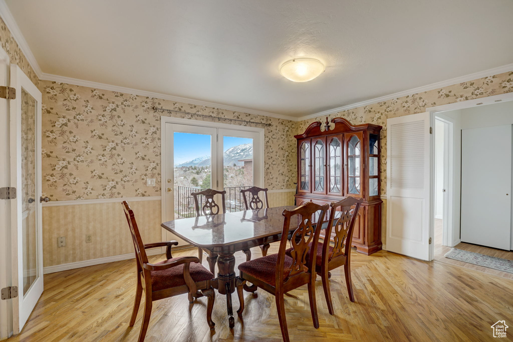 Dining space with crown molding and light hardwood / wood-style flooring