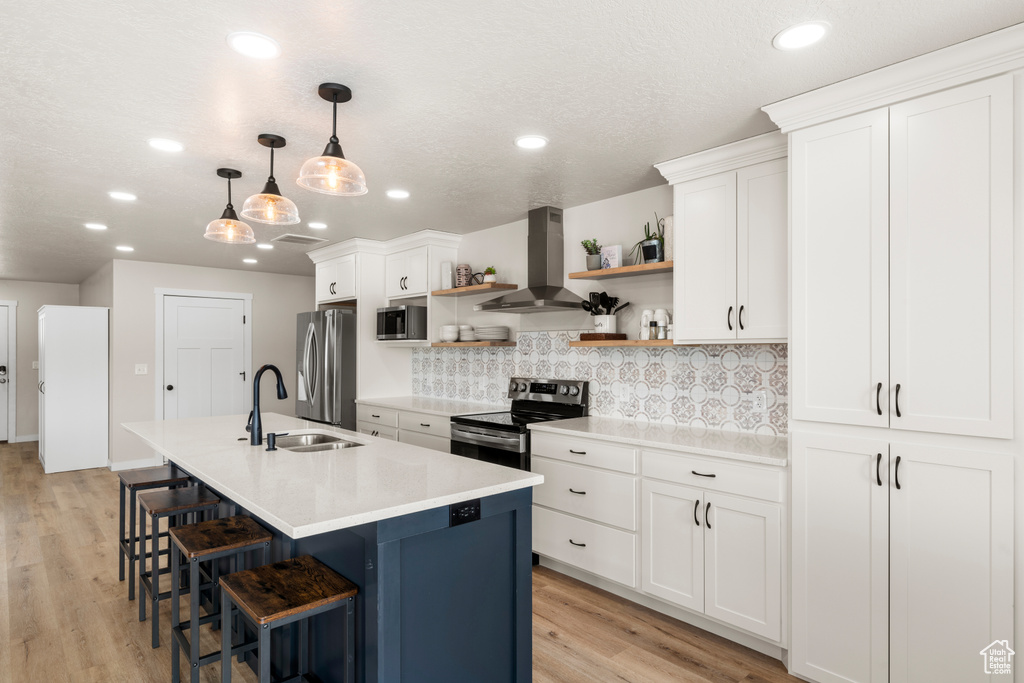 Kitchen with stainless steel appliances, a kitchen breakfast bar, wall chimney range hood, tasteful backsplash, and sink
