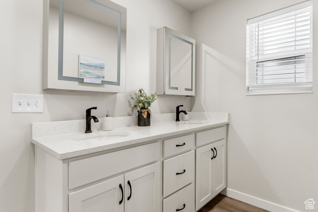 Bathroom with double sink, hardwood / wood-style floors, and vanity with extensive cabinet space