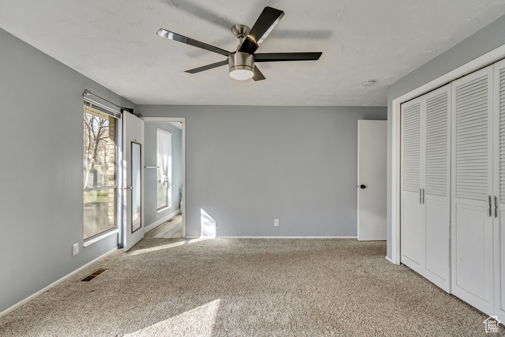 Unfurnished bedroom featuring light colored carpet, a closet, and ceiling fan