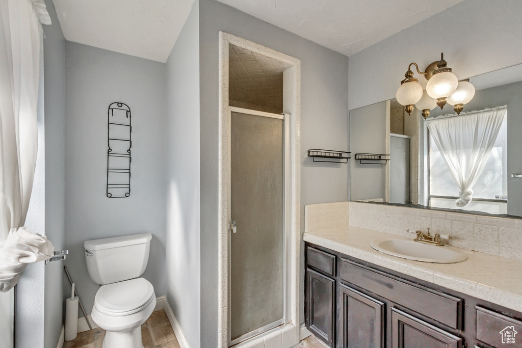 Bathroom with toilet, large vanity, tile floors, and a shower with shower door