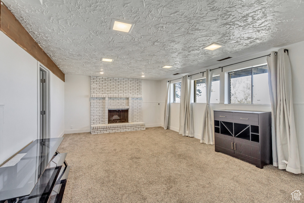 Unfurnished living room with light carpet, a textured ceiling, and a fireplace