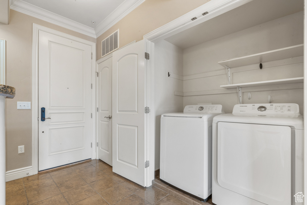 Washroom with dark tile flooring, ornamental molding, and independent washer and dryer