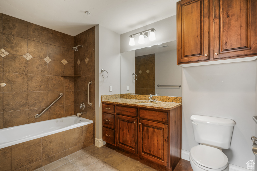 Full bathroom featuring oversized vanity, tile flooring, toilet, and tiled shower / bath