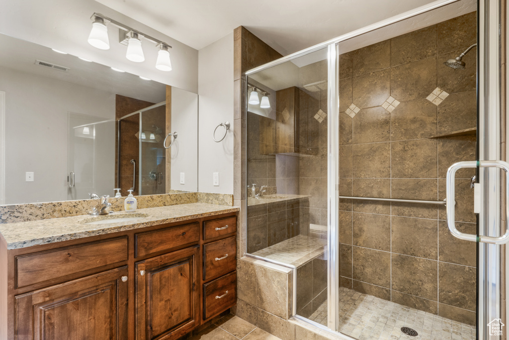 Bathroom with tile floors, vanity, and a shower with shower door