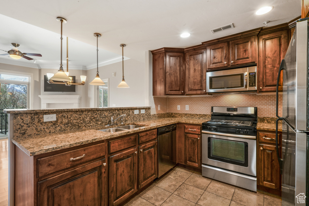 Kitchen featuring appliances with stainless steel finishes, kitchen peninsula, backsplash, ceiling fan with notable chandelier, and sink