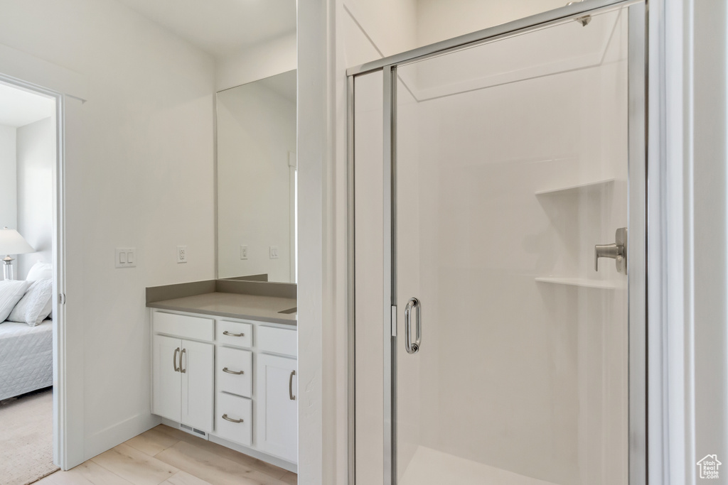Bathroom featuring vanity with extensive cabinet space, a shower with door, and hardwood / wood-style flooring