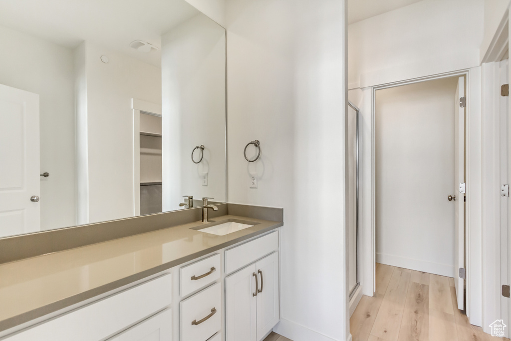 Bathroom featuring a shower with shower door, hardwood / wood-style floors, and vanity