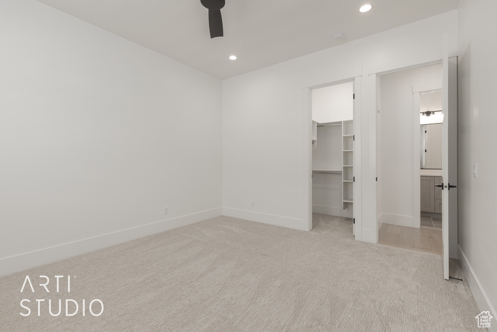 Unfurnished bedroom featuring light colored carpet, a spacious closet, ceiling fan, and a closet