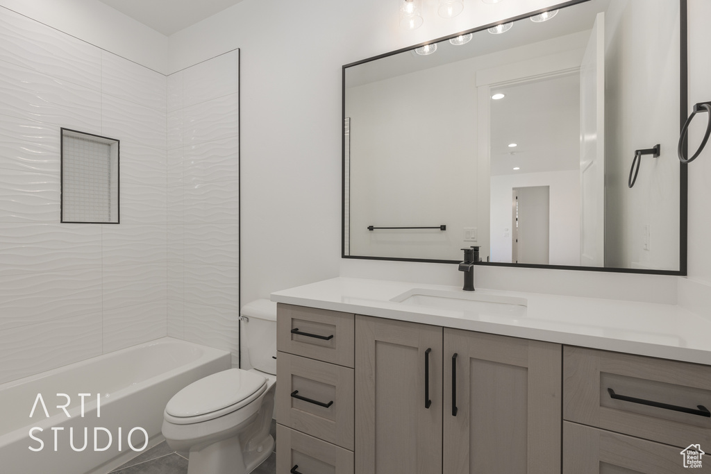 Full bathroom with vanity with extensive cabinet space, toilet, tile floors, and tiled shower / bath combo