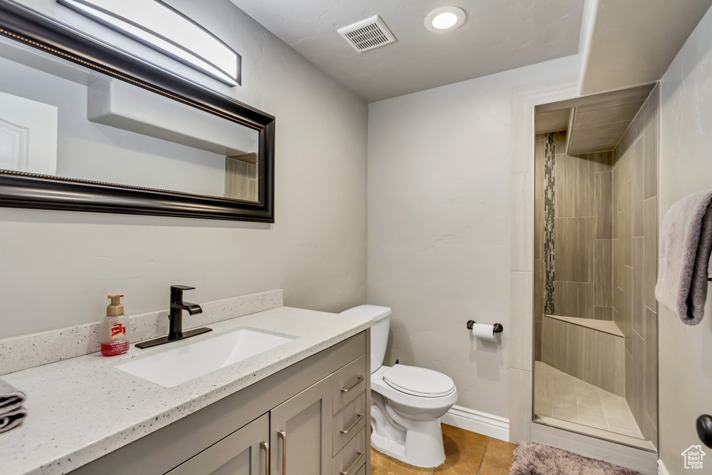 Bathroom featuring toilet, tile flooring, walk in shower, and large vanity
