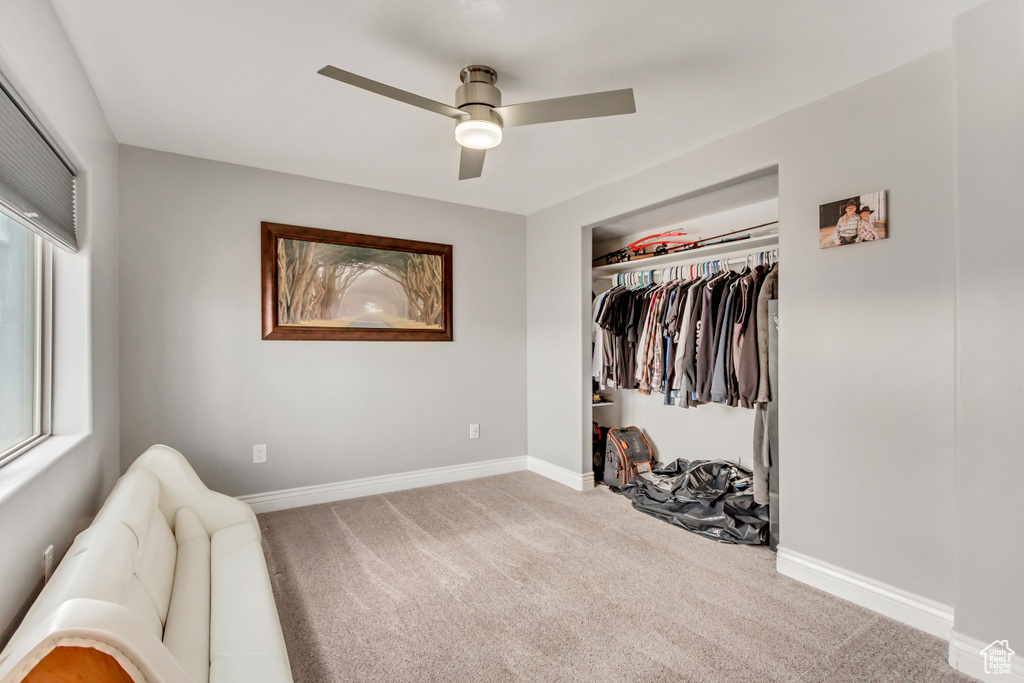 Bedroom with ceiling fan, a closet, and light carpet