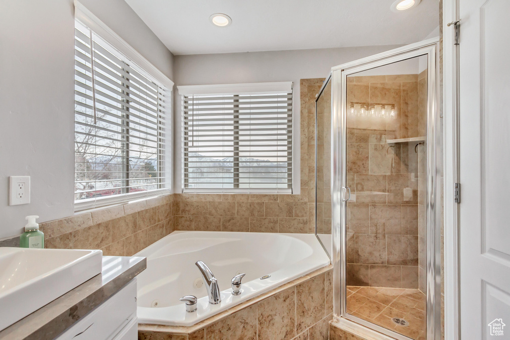 Bathroom featuring vanity, plenty of natural light, and plus walk in shower