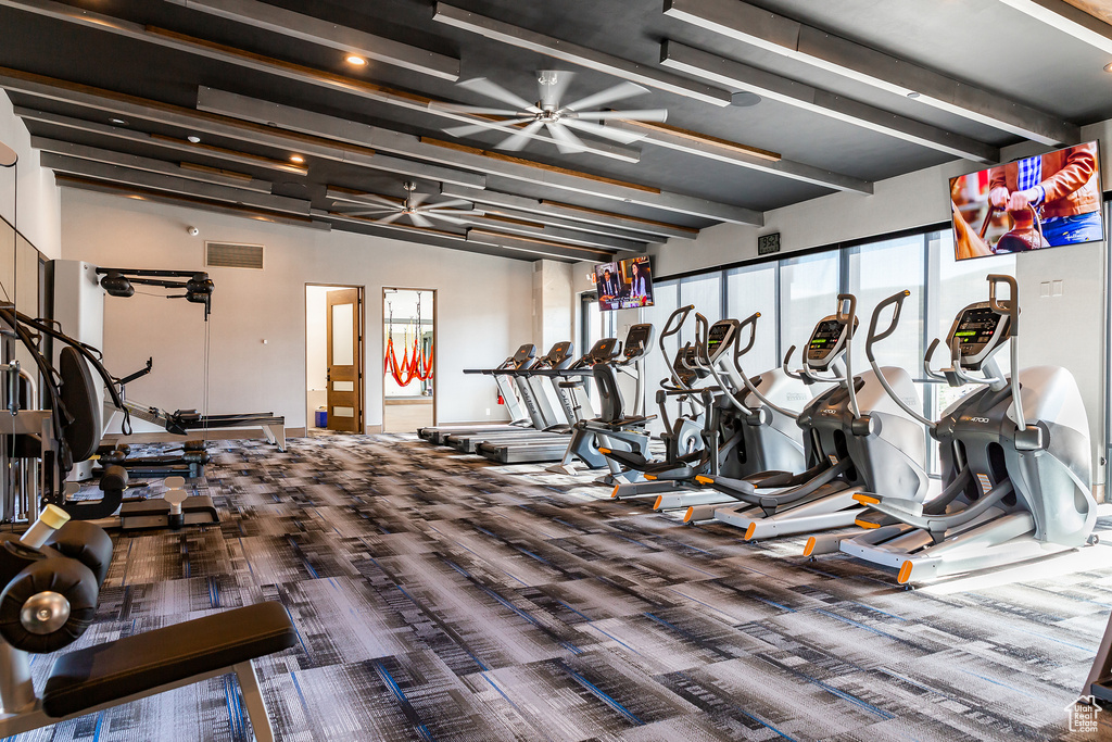 Workout area with ceiling fan and dark colored carpet