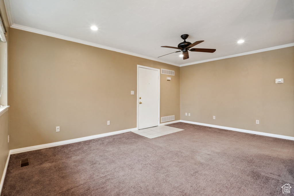 Spare room with light carpet, ornamental molding, and ceiling fan