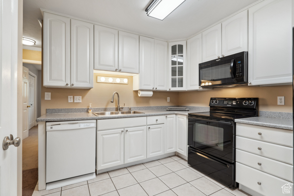 Kitchen featuring sink, white cabinetry, black appliances, and light tile floors