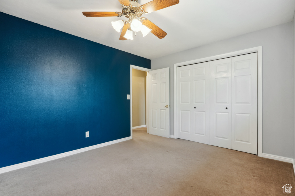 Unfurnished bedroom featuring ceiling fan, a closet, and light colored carpet