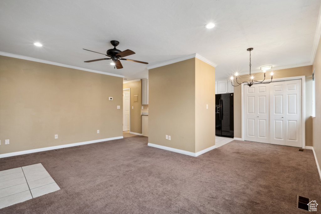 Unfurnished living room featuring crown molding, light carpet, and ceiling fan with notable chandelier