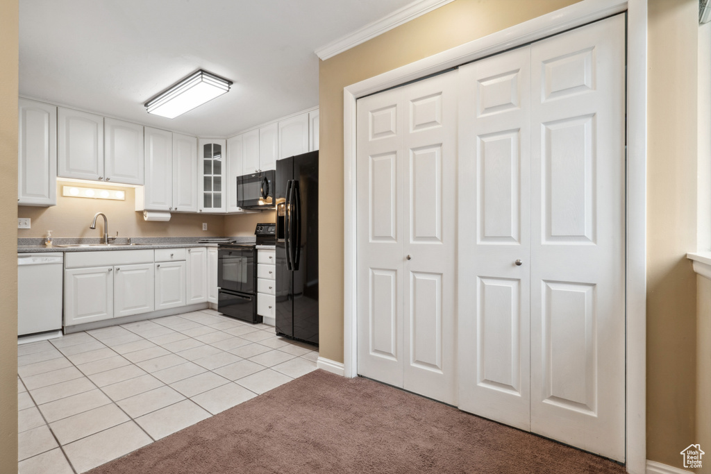 Kitchen with white cabinets, black appliances, sink, and light colored carpet
