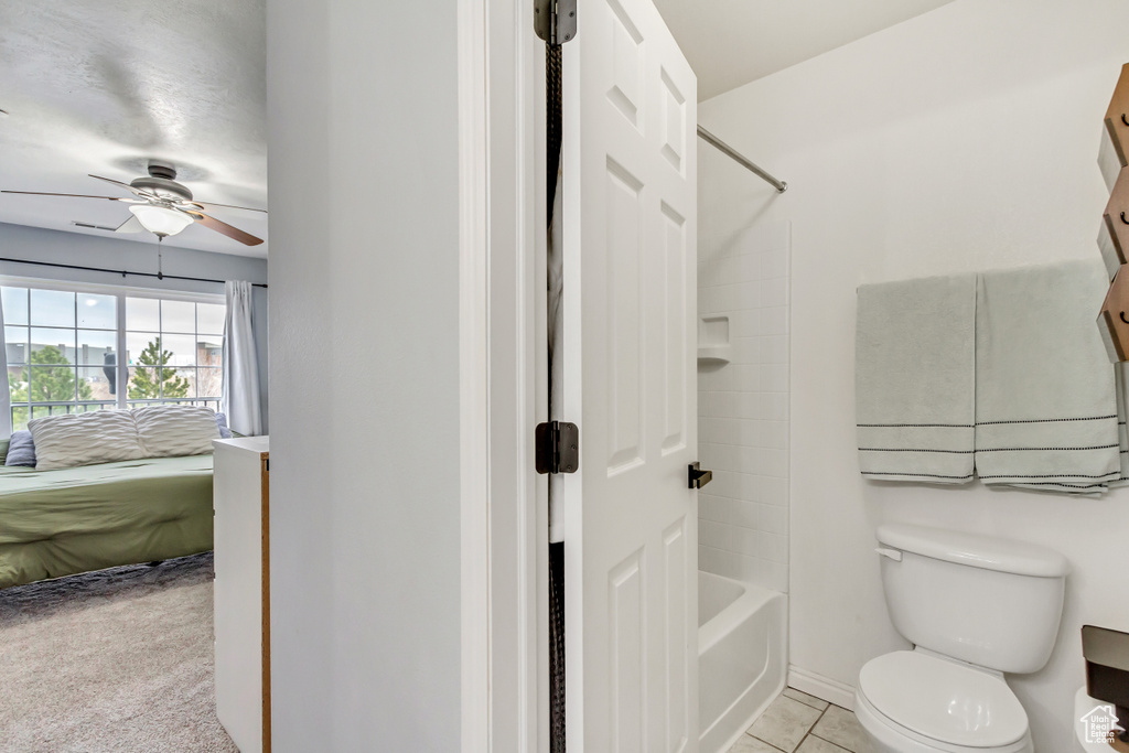 Bathroom featuring shower / washtub combination, toilet, tile flooring, and ceiling fan
