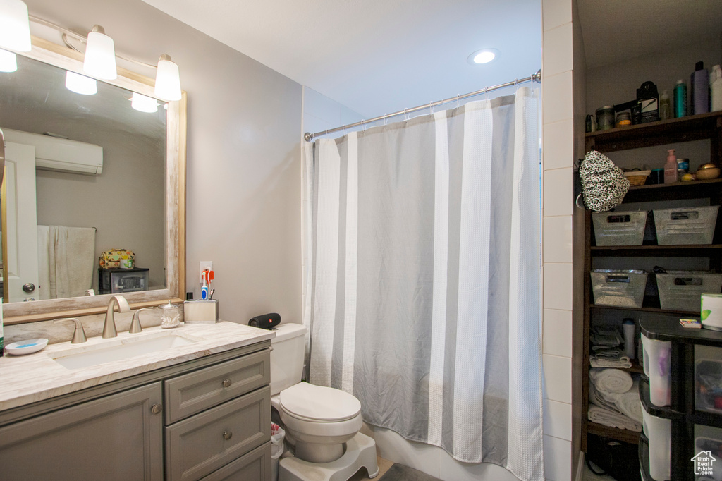 Bathroom with a wall mounted AC, toilet, and vanity