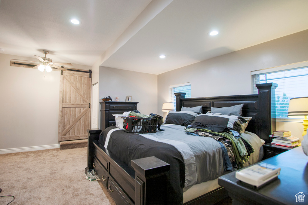 Bedroom featuring a barn door, light carpet, and ceiling fan
