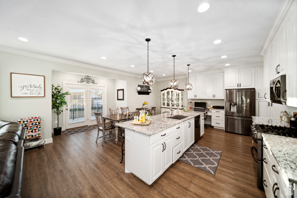 Kitchen with stainless steel appliances, a kitchen breakfast bar, white cabinets, a kitchen island with sink, and dark hardwood / wood-style floors